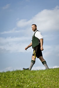 Low angle view of man walking on field against sky