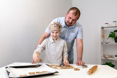 Father helps his son make cookies for the holiday.