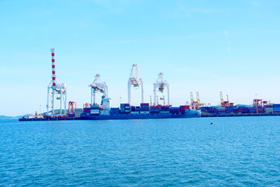 Cranes at commercial dock against blue sky