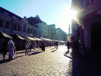 People walking on city street at sunset