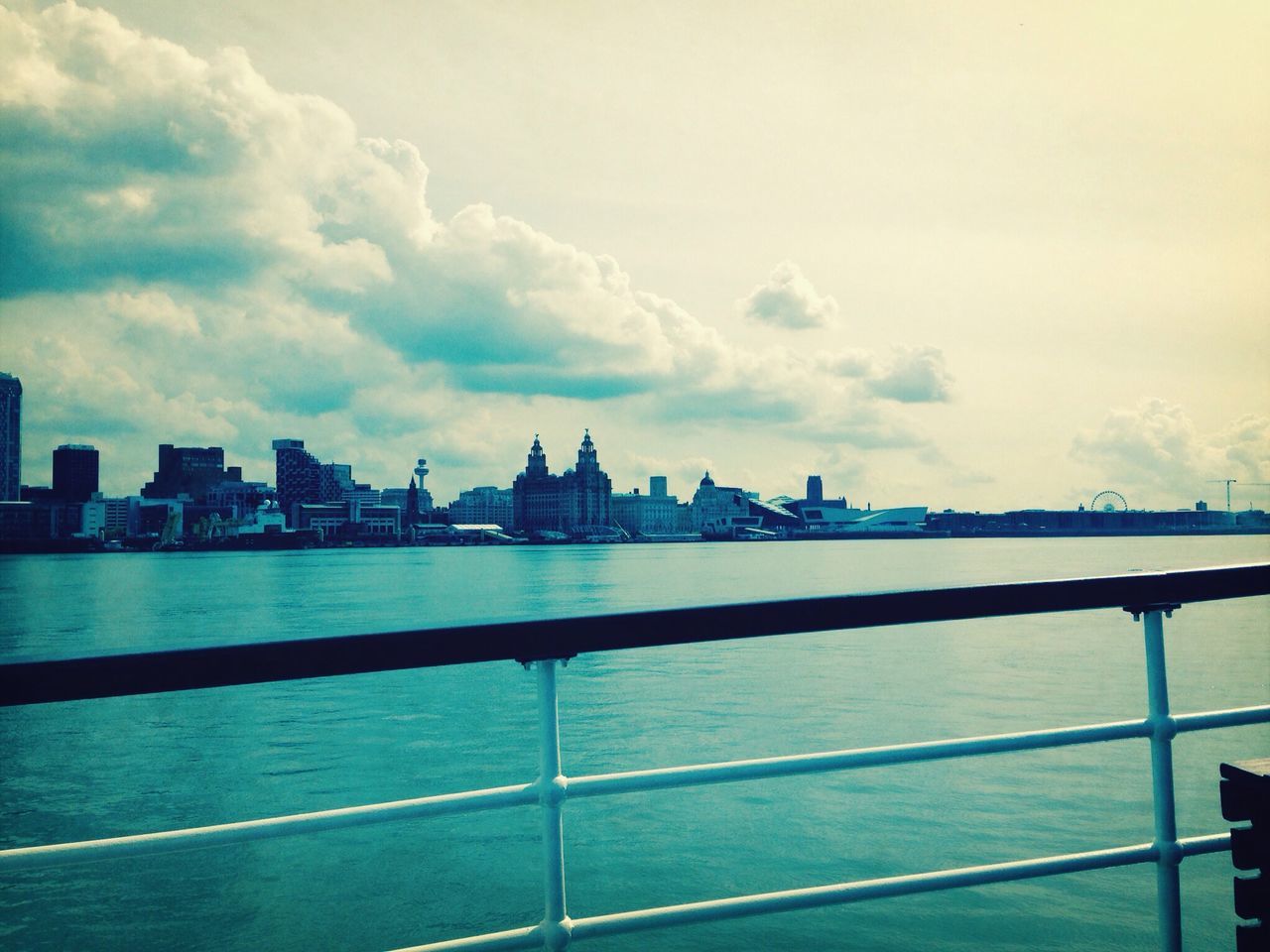 architecture, building exterior, built structure, sky, water, city, cityscape, cloud - sky, river, sea, cloud, railing, cloudy, urban skyline, travel destinations, skyline, waterfront, skyscraper, tower, day