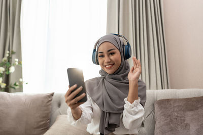 Young woman using mobile phone while sitting on sofa at home