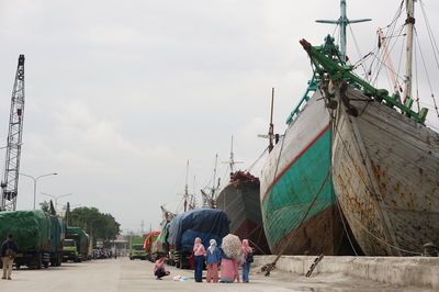 People in harbor by sea against sky