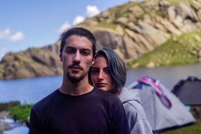 Portrait of couple standing against lake and mountain