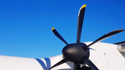 Low angle view of airplane jet engine against clear blue sky