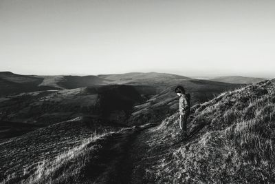 Boy walking on field against clear sky