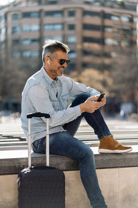 Man using mobile phone while sitting in city