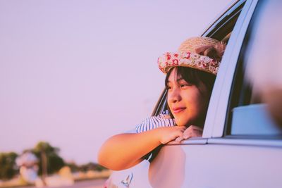 Thoughtful teenage girl leaning on car window