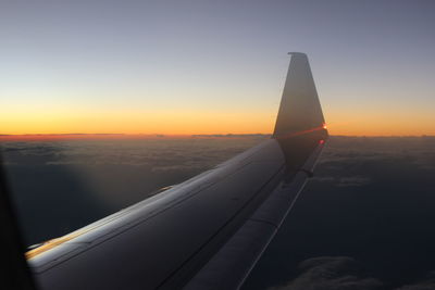 Close-up of airplane wing against sky during sunset