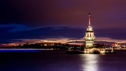 Illuminated city at waterfront during sunset