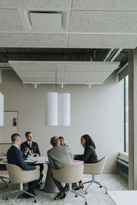 Multiracial male and female colleagues discussing strategy in board room during meeting