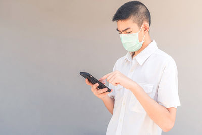 Midsection of man using smart phone against white background