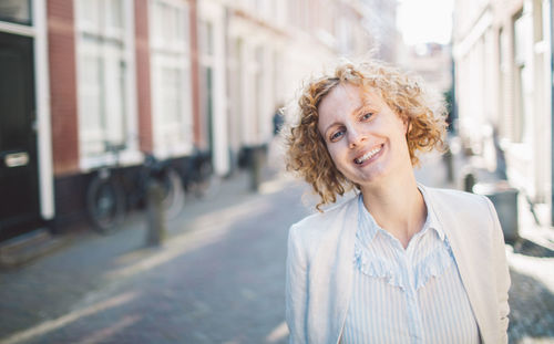 Portrait of cheerful woman standing on street in city