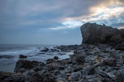 Rock formation on beach against sky