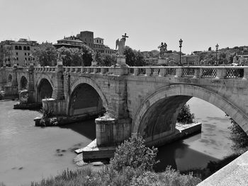 Arch bridge over river against clear sky