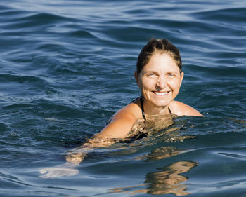 Portrait of smiling woman swimming in sea
