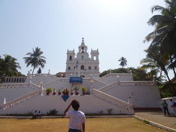 Rear view of people walking by palm trees against sky