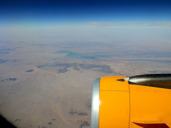 Close-up of airplane wing over landscape