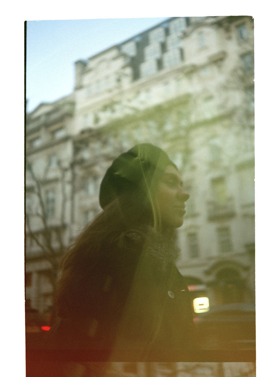 PORTRAIT OF WOMAN LOOKING AT CITY BUILDING