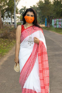 A pretty indian woman in red saree and long hair wearing protective cotton nose mask posing 