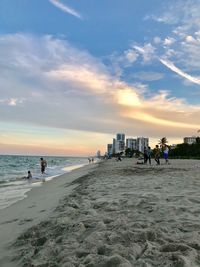People on beach against sky during sunset