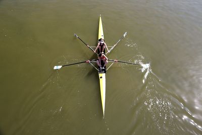 High angle view of female friends rowing boat in lake