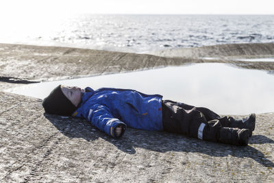 Boy lying on rocks at sea