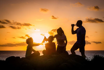 Happy family toasting at beach during sunset
