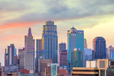 Modern buildings in city against sky during sunset