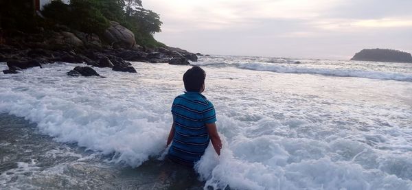 Rear view of man looking at sea against sky