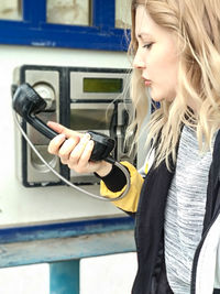 Young woman holding camera while standing at home