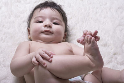 Portrait of cute baby girl lying on bed