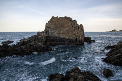 Rock formation on beach against sky