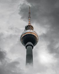 Low angle view of communications tower and building against sky