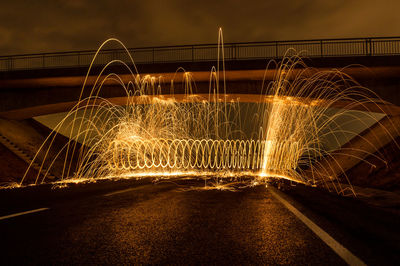 Light trails on bridge against sky at night