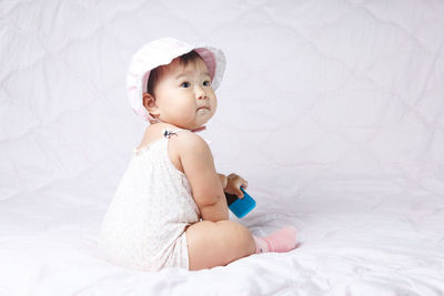 Cute baby girl sitting on bed at home