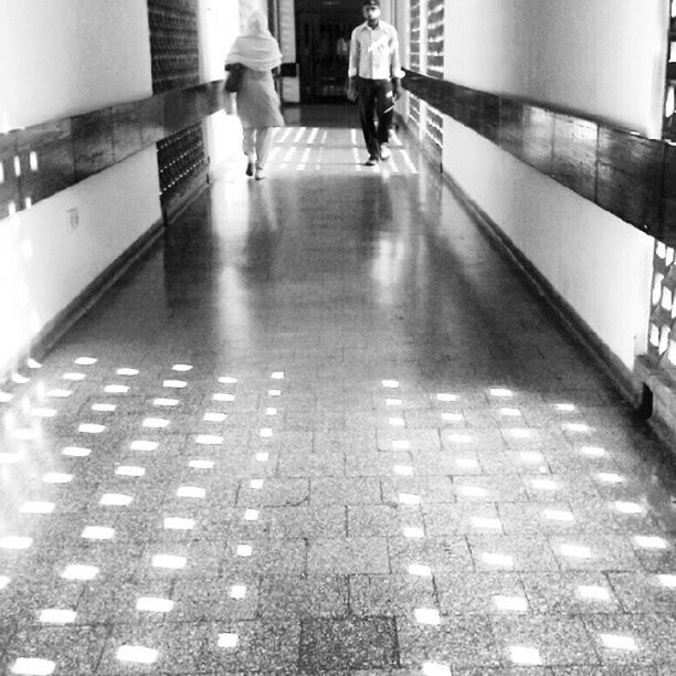 walking, lifestyles, indoors, men, architecture, low section, tiled floor, built structure, leisure activity, person, full length, the way forward, flooring, city life, rear view, sunlight, corridor