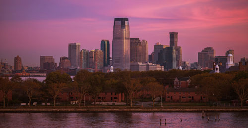 River amidst buildings against sky during sunset