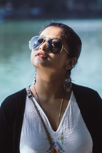 Close-up of young woman wearing sunglasses while standing against lake