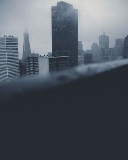 Buildings in city against cloudy sky