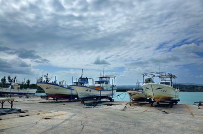 Boats moored at harbor against sky