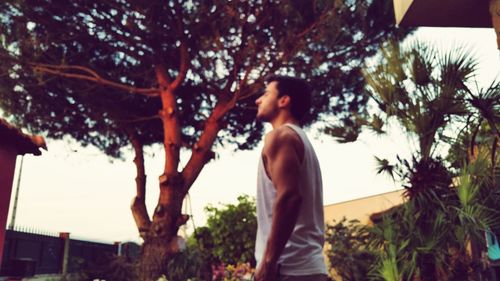 Rear view of woman standing by tree against sky