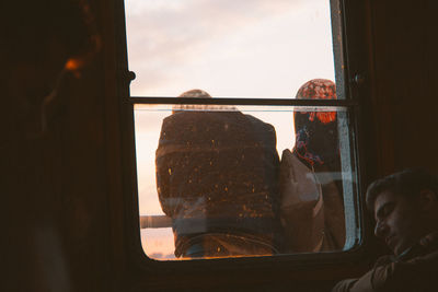 Rear view of people looking through window