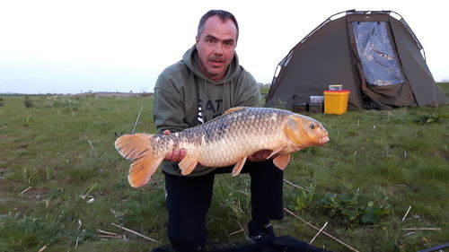 Full length of man holding fish at shore