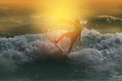 Woman splashing water in sea during sunset