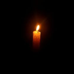 Lit candle in dark room