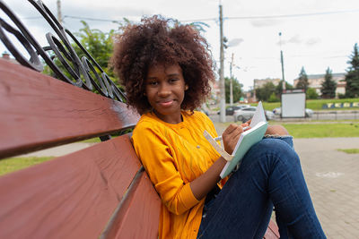 Portrait of smiling young woman sitting outdoors