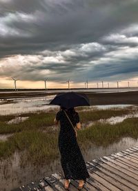 Rear view of woman on field during rainy season