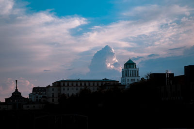 Buildings in city against cloudy sky