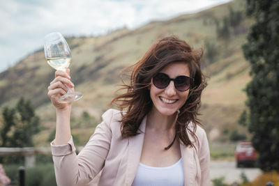 Portrait of smiling young woman holding sunglasses